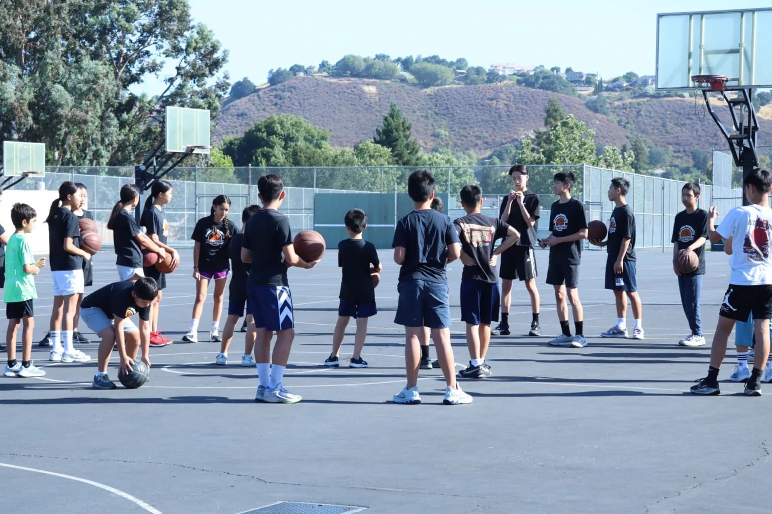 A group of campers and coaches spread across an outdoor court.